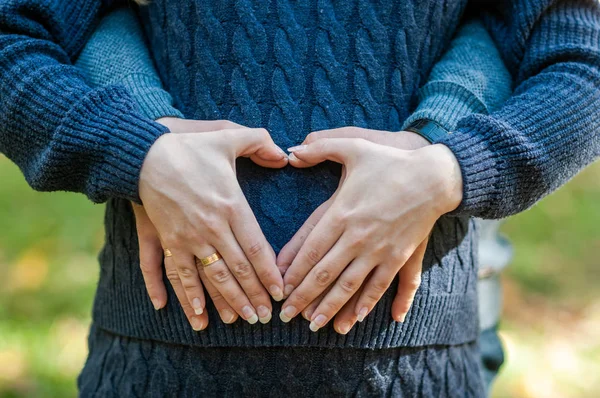 La mujer embarazada y el hombre se toman de la mano en forma de corazón —  Fotos de Stock