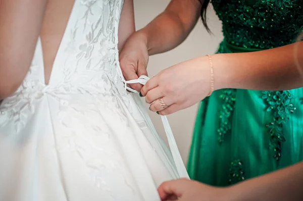 Družičky pomáhají nevěstě nosit svatební šaty — Stock fotografie