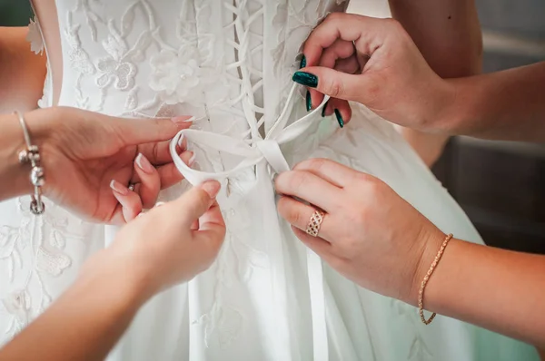 Подружки невесты помогают невесте носить свадебное платье — стоковое фото