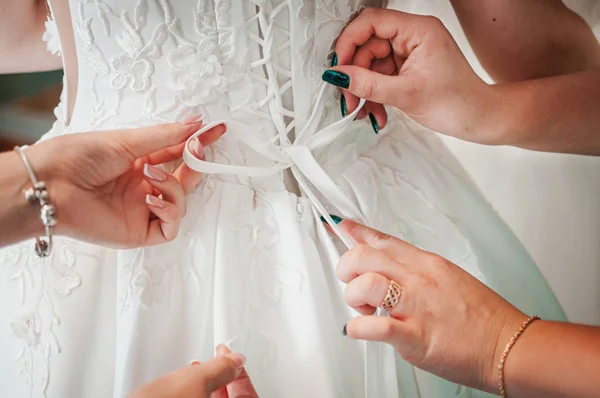 Las damas de honor ayudan a la novia a usar vestido de novia — Foto de Stock