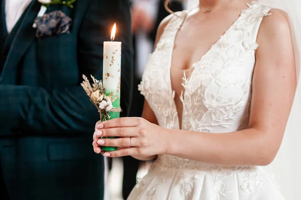 Nevěsta a ženich drží v kostele svíčky — Stock fotografie