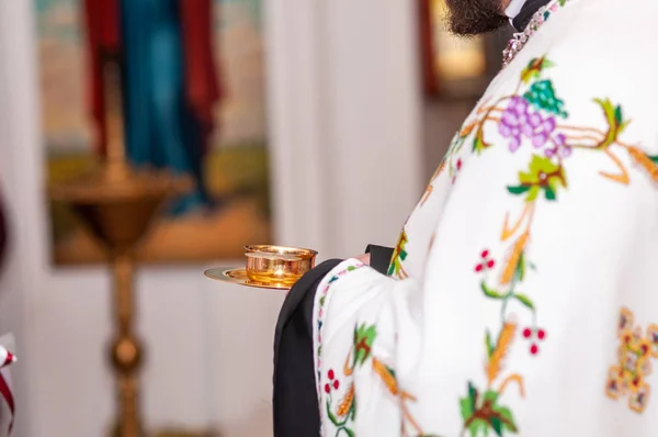 Sacerdote segurando copo de ouro com vinho nas mãos — Fotografia de Stock