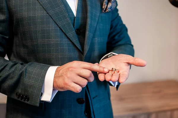 Groom segurando anéis de casamento dourados na mão — Fotografia de Stock