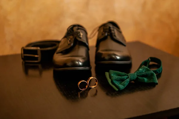 Paar schoenen gouden trouwringen en groene tieboog — Stockfoto