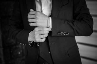 Bir damat gömleğe kol düğmesi bağlıyor.