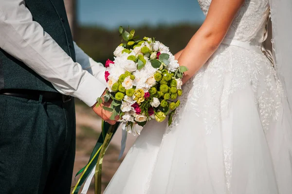 Жених и невеста держат цветной свадебный букет в руке — стоковое фото