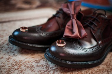 Brown man shoes tiebow and pair of gold wedding rings