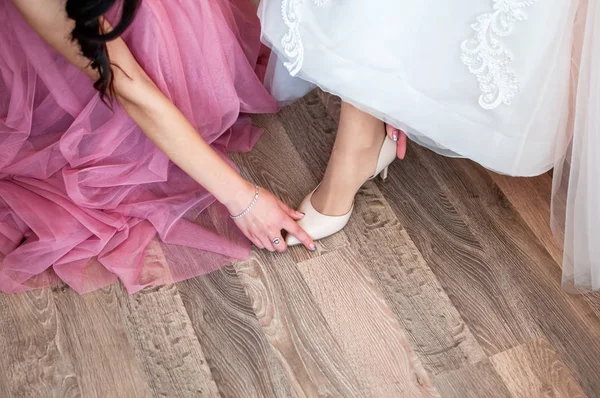 Подружка невесты помогает невесте надеть элегантные туфли — стоковое фото