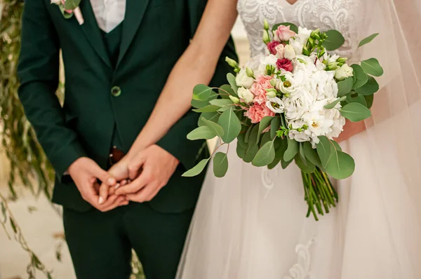 Manos de novia y novio con ramo de flores — Foto de Stock