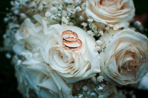 Anneaux de mariage en or couchés sur le bouquet de fleurs blanches — Photo