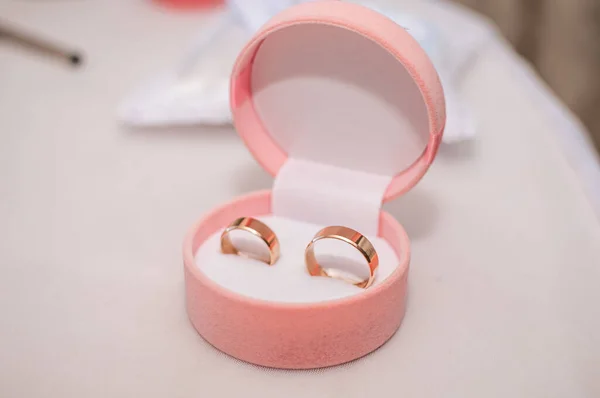 Un par de anillos de boda de oro en la caja rosa — Foto de Stock