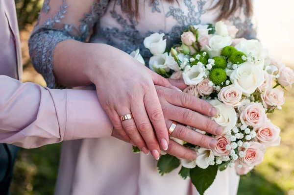 Τα χέρια της νύφης και του γαμπρού με μπουκέτο λουλούδια — Φωτογραφία Αρχείου