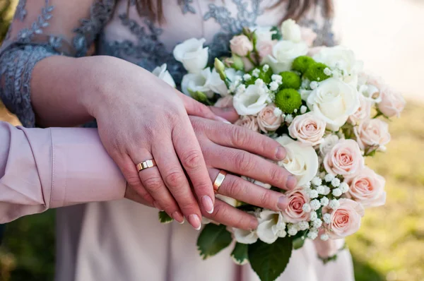 Handen van bruid en bruidegom met boeket van bloemen — Stockfoto