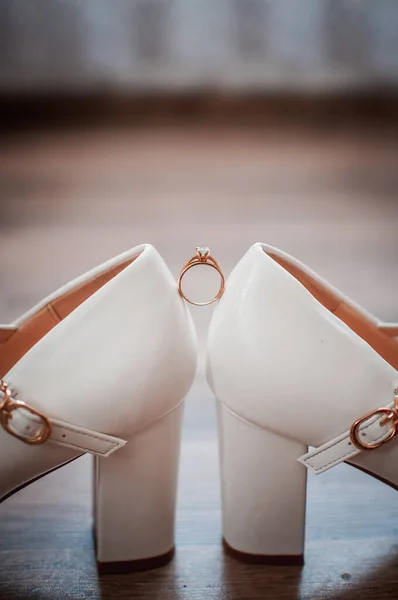 Anillo de boda de oro entre un par de zapatos blancos — Foto de Stock