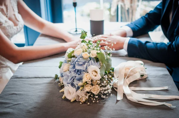Bir buket çiçek ve masanın üstünde iki el. — Stok fotoğraf