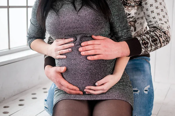 Erkek ve kadın hamile karnında el ele tutuşuyorlar. — Stok fotoğraf