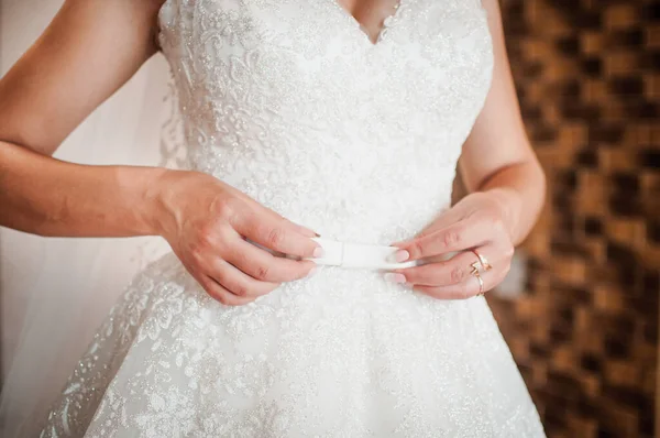 Mains de mariée sur la robe de mariée blanche — Photo