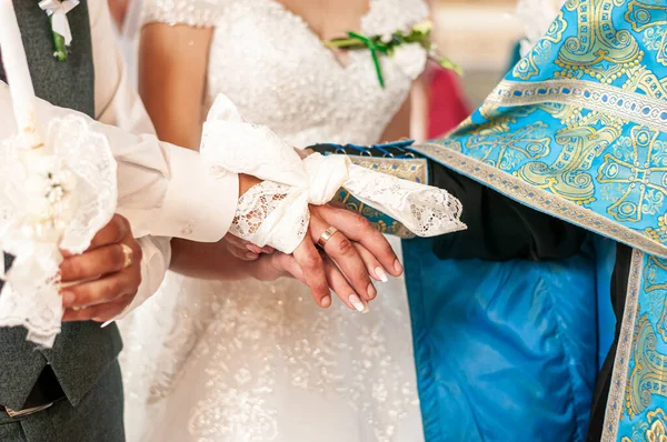 新娘和新郎的手被毛巾包裹在教堂里 — 图库照片