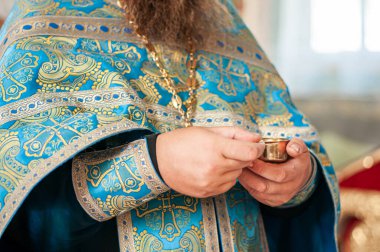 Elinde gümüş kadehle şarap taşıyan bir rahip.