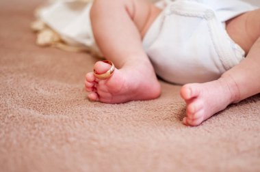 Yeni doğan çocuğun büyük parmaklarında altın yüzükler