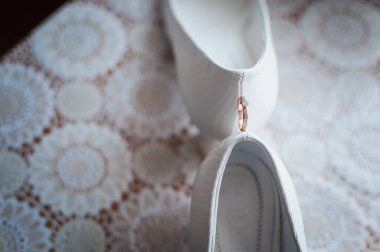 Beyaz bir ayakkabı çifti arasında altın alyans çifti