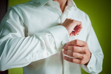 Bir damat gömleğe kol düğmesi bağlıyor.