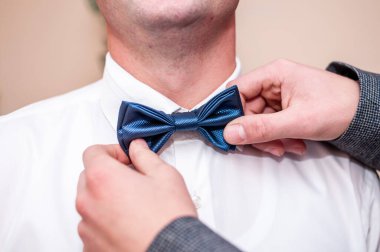 Erkek damadın boynunda mavi papyon tutar.