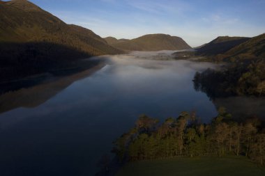 İngiltere 'nin kuzeybatısındaki İngiliz Gölü Bölgesi' ndeki Buttermere gölünün etrafında şafak sisi yükseliyor. Bitişikteki Buttermere köyü adını gölden alır. Tarihsel olarak Cumberland, Cumbria 'da yer alan bir şehirdir. Sahibi kim? 