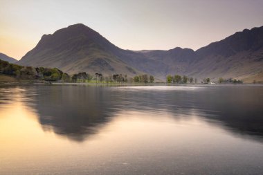 Buttermere 'de şafak vakti, İngiltere' nin kuzeybatısındaki İngiliz Lake District gölünde. Bitişikteki Buttermere köyü ismini gölden alır..