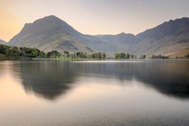Buttermere 'de şafak vakti, İngiltere' nin kuzeybatısındaki İngiliz Lake District gölünde. Bitişikteki Buttermere köyü ismini gölden alır..