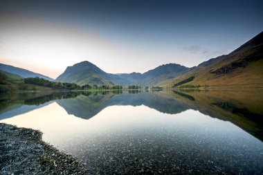 Buttermere 'de şafak vakti, İngiltere' nin kuzeybatısındaki İngiliz Lake District gölünde. Bitişikteki Buttermere köyü ismini gölden alır..