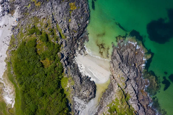 Drone footage of waves lapping up onto rocks in Portuairk Bay, Scotland