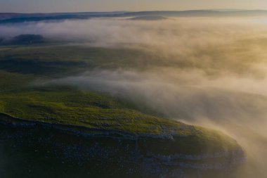 Malham 'ın kireçtaşı kayalıklarında sisli bir sabahı yakalayan bir dron atışı.