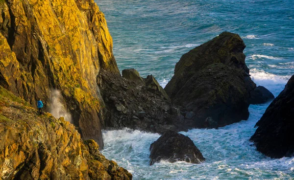 一名徒步旅行者在英国康沃尔的九军山湾观看海浪冲撞岩石 — 图库照片