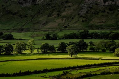 Fırtınalı gökyüzü ve parlak bir güneş ışığı İngiliz Gölü Bölgesi 'ndeki Langdale Pikes' in üzerinde.