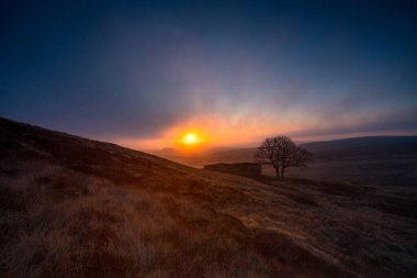 Top Withens ya da Top Withins 'in Gündoğumu, bu çiftlik evi Uğultulu Tepeler' le ilişkilendiriliyor..