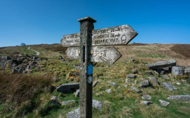 A footpath sign in english and japanese giving directions to Top Withens Haworth or Withins clipart