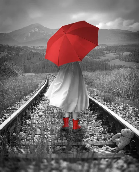 女孩有一把红色的雨伞在铁轨上。丢失的泰迪熊。数字 — 图库照片