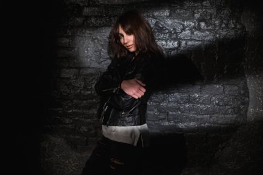 karanlık tuğla duvara deri ceketli güzel kadın