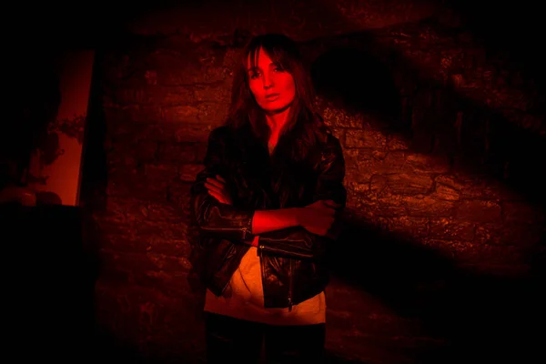 Bela mulher na jaqueta de couro contra a parede de tijolo de escuro — Fotografia de Stock