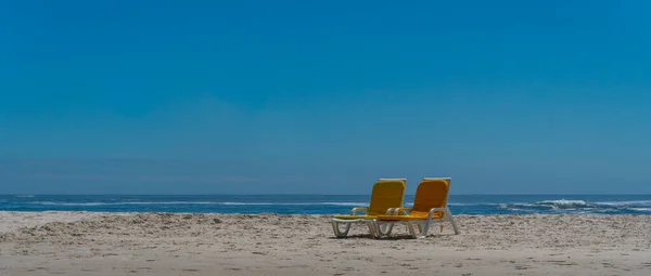  İki boş plaj banklı plaj sahnesi. Seçici odaklanma. Bazı ülkelerde koronavirüs veya covid 19 nedeniyle sosyal uzaklık ve boş yer kavramı.