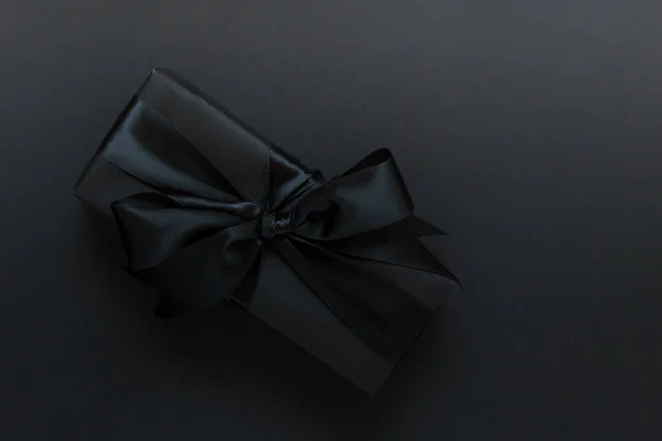 Подарок с черным бантом на черном фоне — стоковое фото