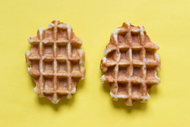Two belgian round waffles on yellow backgound