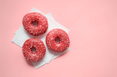 Three glazed pink donuts with sugar sprinkles