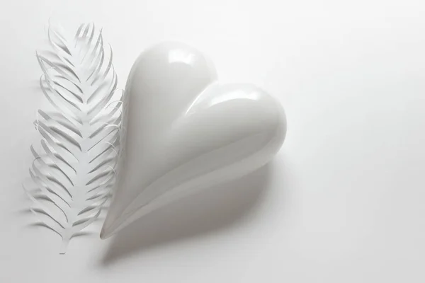 Coração porcelein branco com pena de papel — Fotografia de Stock