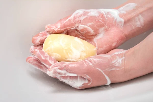 Washing hands sanitizing with soap bar. Hands with soapy foam on white background.