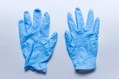 Mavi arka planda buruşmuş bir çift tıbbi eldiven.