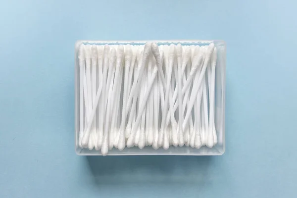 Cotton swabs in plastic box on blue backgound.