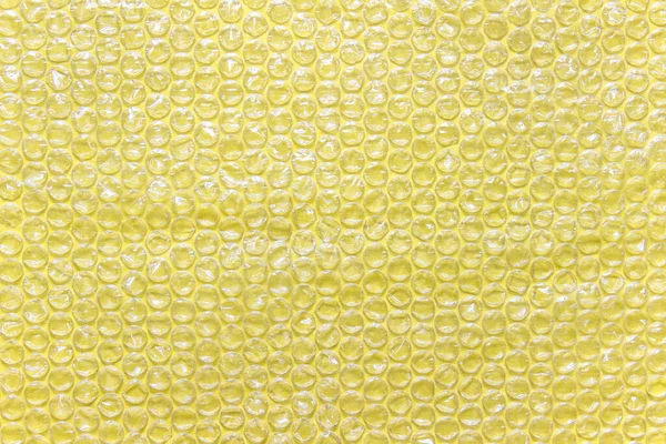 黄色のバブルラップ空気充填透明包装箔黄色の背景に配置 — ストック写真