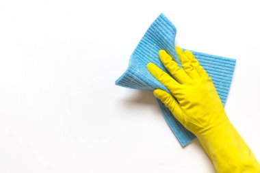 Beyaz arka planda mavi mikrofiber kumaşlı sarı lastik eldivenli kadın eli. Boş alanı kopyalayan fotoğraf.
